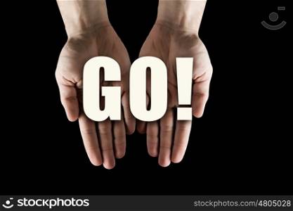 Conceptual word in palms. Male hands on dark background showing in palms word GO