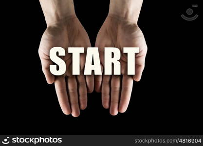 Conceptual word in palms. Male hands on dark background showing in palms word start concept