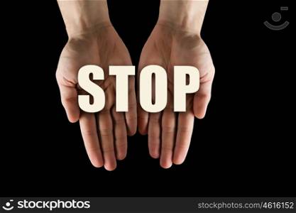 Conceptual word in palms. Male hands on dark background showing in palms word stop
