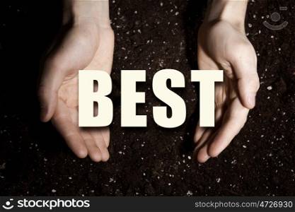 Conceptual word in palms. Male hands on soil background showing in palms idea word best