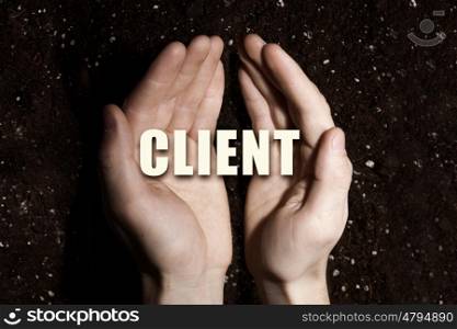 Conceptual word in palms. Male hands on soil background showing in palms idea word client
