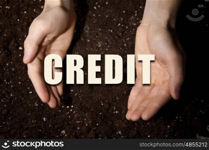 Conceptual word in palms. Male hands on soil background showing in palms idea word credit