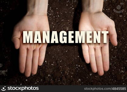 Conceptual word in palms. Male hands on soil background showing in palms idea word management