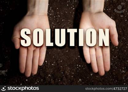 Conceptual word in palms. Male hands on soil background showing in palms idea word solution