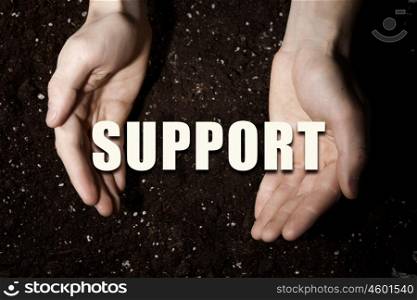 Conceptual word in palms. Male hands on soil background showing in palms idea word support