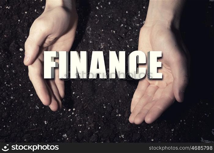 Conceptual word in palms. Male hands on soil background showing in palms word finance