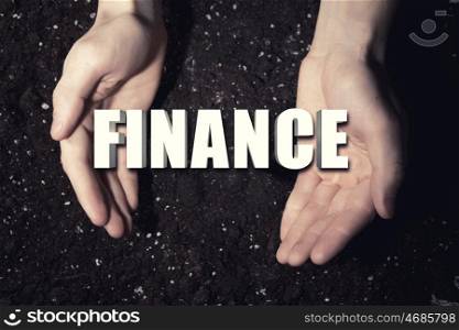 Conceptual word in palms. Male hands on soil background showing in palms word finance