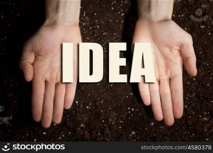 Conceptual word in palms. Male hands on soil background showing in palms word idea