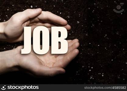 Conceptual word in palms. Male hands on soil background showing in palms word job