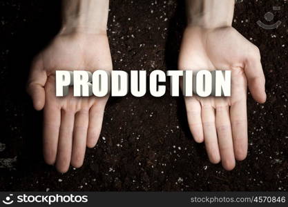 Conceptual word in palms. Male hands on soil background showing in palms word production