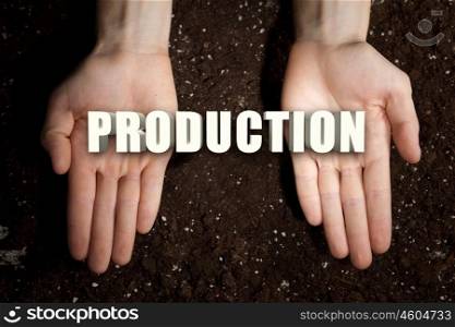 Conceptual word in palms. Male hands on soil background showing in palms word production