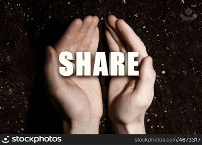 Conceptual word in palms. Male hands on soil background showing in palms word share