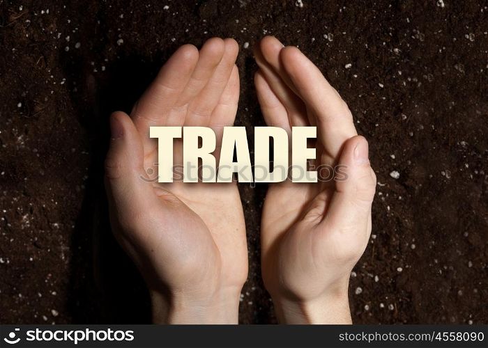 Conceptual word in palms. Male hands on soil background showing in palms word trade