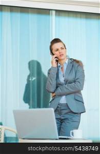 Concerned business woman talking mobile phone on terrace