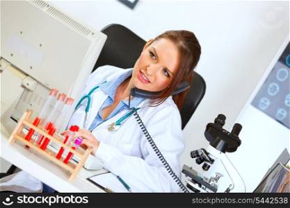 Concerned female doctor talking on phone and looking in monitor&#xA;