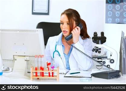 Concerned medical doctor woman talking on phone and looking in monitor&#xA;