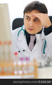 Concerned medical doctor working on computer at office