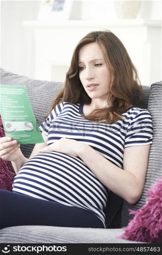 Concerned Pregnant Woman Reading Leaflet With Medical Advice