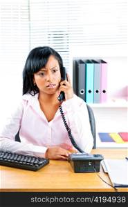 Concerned young black business woman on phone at desk in office