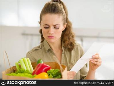 Concerned young housewife examines check after shopping