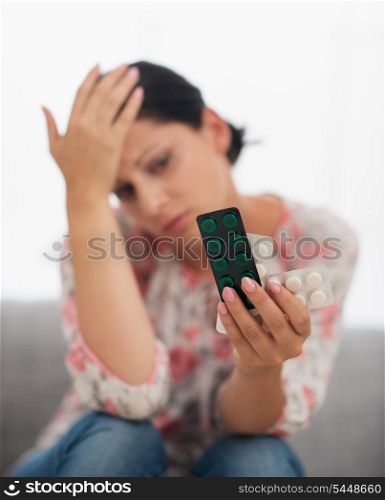 Concerned young woman looking on pack of pills