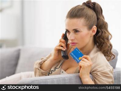 Concerned young woman with credit card talking phone