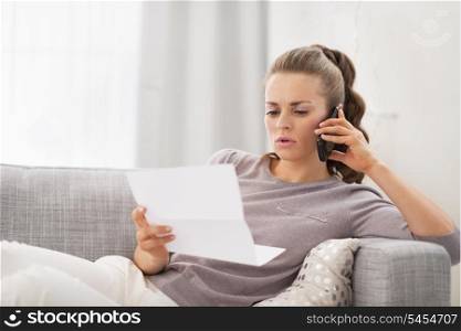 Concerned young woman with letter and talking cell phone