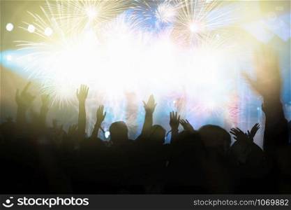 Concert crowd in silhouettes of Music fanclub with show hand action for celebrate with fireworks, happy new year and christmas concept