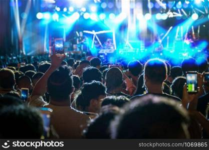 Concert crowd of Music fanclub hand holding mobile smart phone taking video record or Live stream with super star songer, musical and concert concept