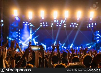 Concert crowd of Music fanclub hand using cellphone taking video record or Live stream with superstar songer, happy new year, christmas and festival concept
