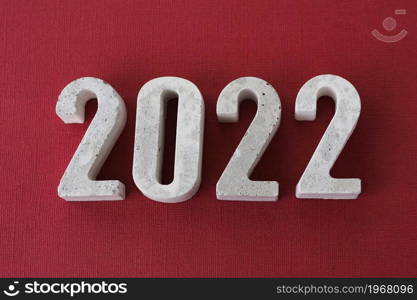 concrete numbers 2022 on burgundy background.