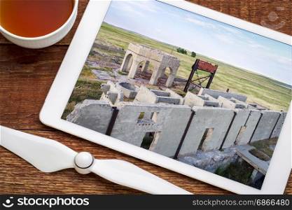 concrete ruins of one of five reduction plants and pump stations manufacturing potash during World War I near Antioch, Nebraska, reviewing aerial image on digital tablet