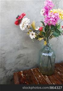 Concrete wall with colorful flowers in vase on a wooden table, decoration in modern room beautiful various colors. Concrete wall with colorful flowers in vase on a wooden table, decoration in modern room