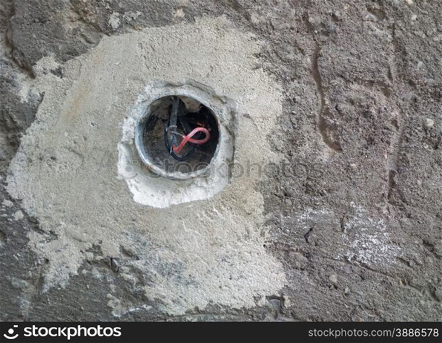 Concrete wall with exposed wires in wall socket