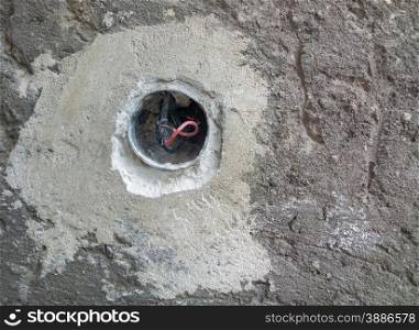 Concrete wall with exposed wires in wall socket