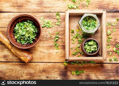 Condiment made from dried green parsley on on wooden table. Dried parsley leaves for cooking