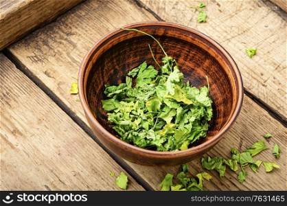 Condiment or spice made from dried parsley on on vintage wooden background. Dried parsley seasoning