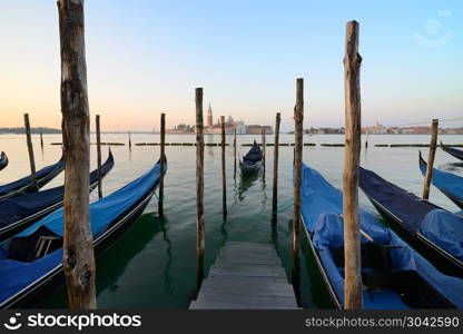 Condolas and wooden pier in Venice, Italy. Condolas and wooden pier