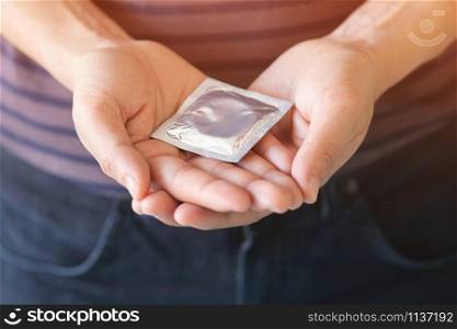 Condom ready to use in female hand, give condom safe sex concept on the bed Prevent infection and Contraceptives control the birth rate or safe prophylactic. World AIDS Day, Leave space for text.