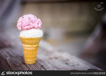 Cone of coconut and strawberry ice-cream on wooden background