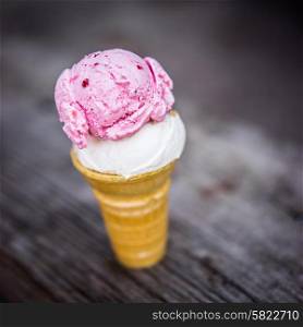Cone of coconut and strawberry ice-cream on wooden background