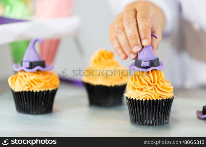 Confectioner decorate some cupcakes in the kitchen