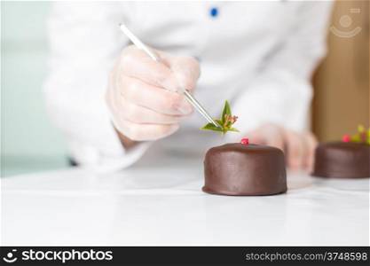 Confectioner putting the last ornament to a cake