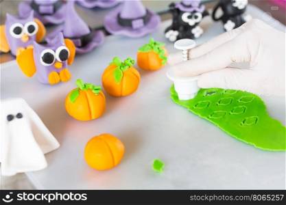 Confectioner working on the figures of Halloween with fondant paste
