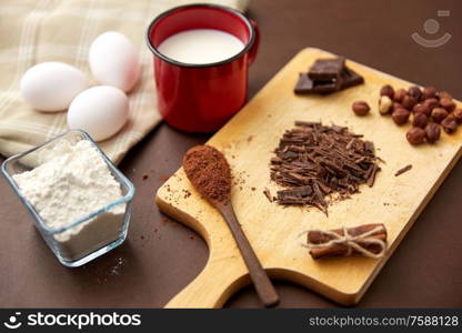 confectionery and culinary concept - chocolate, cocoa powder, hazelnuts with milk, eggs and flour on brown background. chocolate, cocoa powder, milk, eggs and flour