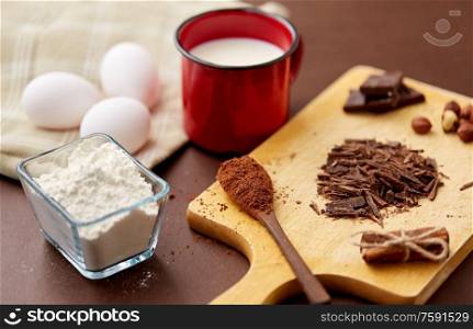 confectionery and culinary concept - chocolate, cocoa powder, hazelnuts with milk, eggs and flour on brown background. chocolate, cocoa powder, milk, eggs and flour