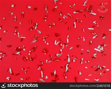 Confetti foil pieces on a red background. Abstract festive backdrop.. Confetti foil pieces on red background. Abstract festive backdrop.