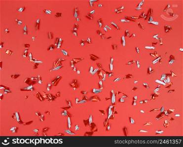 Confetti foil pieces on a red background. Abstract festive backdrop.. Confetti foil pieces on red background. Abstract festive backdrop.