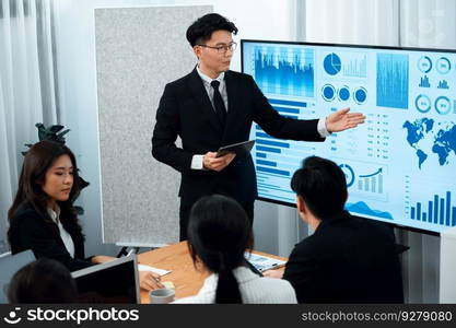 Confidence and asian businessman give presentation on financial analyzed by business intelligence in dashboard report to other people in board room meeting to promote harmony in workplace.. Confidence and young asian businessman give presentation to promote harmony.