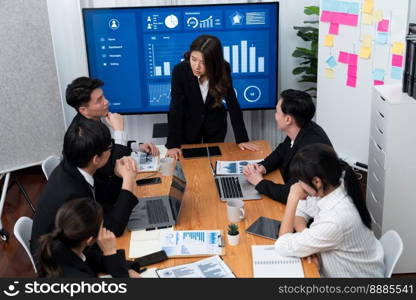 Confidence and young asian businesswoman give presentation on financial business strategy in dashboard report display on screen to colleagues in conference room meeting as harmony in workplace concept. Businesswoman give presentation on dashboard data on screen at harmony office.